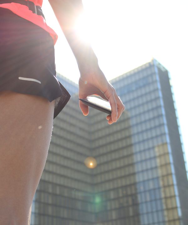 Coureuse en tenue légère courant au lever du soleil avec une ceinture de running contenant une petite gourde, symbole de l’hydratation estivale.