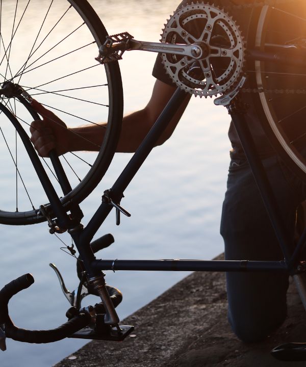 Cycliste arrêtant son vélo pour réparer une crevaison, avec une mini-pompe et une chambre à air à ses pieds.