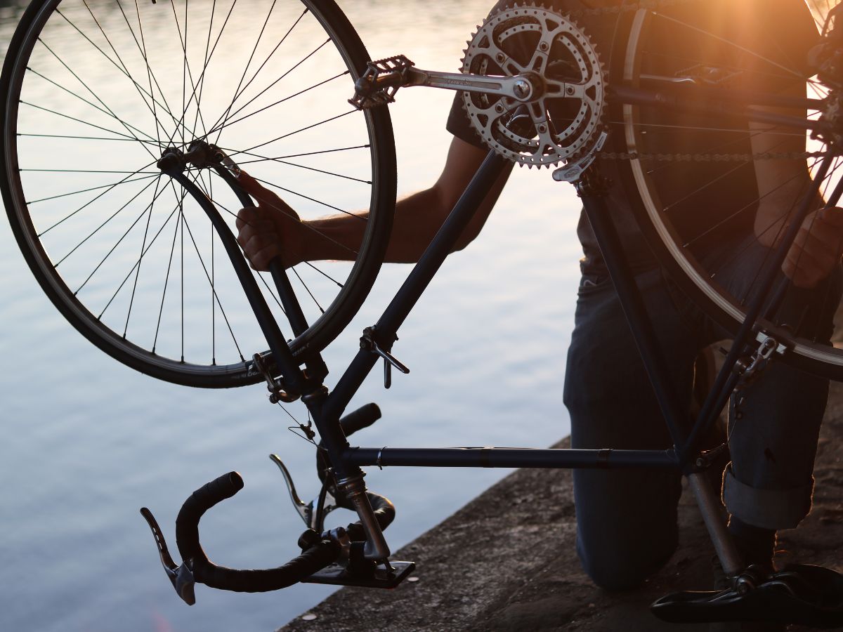 Cycliste arrêtant son vélo pour réparer une crevaison, avec une mini-pompe et une chambre à air à ses pieds.