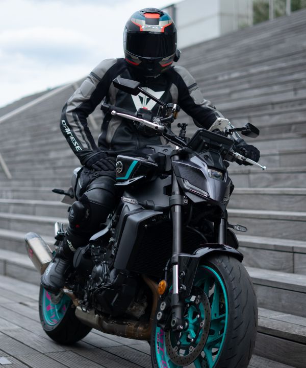 Moto avec deux personnes en virage, montrant l'adaptation de la conduite avec un passager à l’arrière.