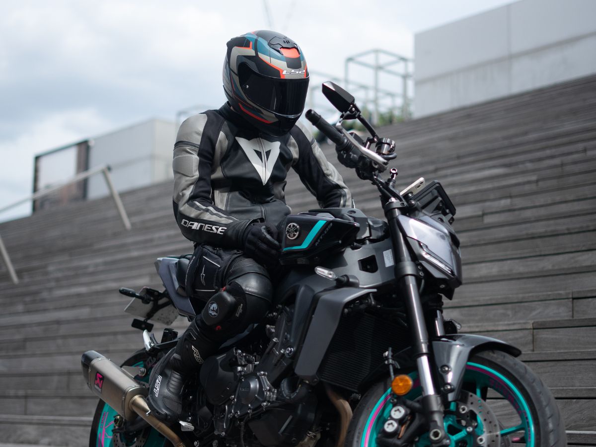 Passager tapant l'épaule du pilote, illustrant la communication gestuelle pendant un trajet à moto en duo.