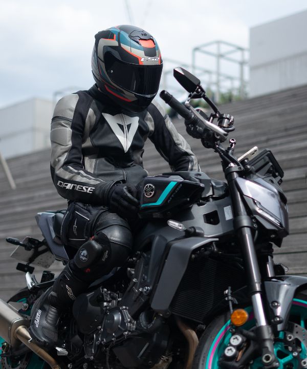 Passager tapant l'épaule du pilote, illustrant la communication gestuelle pendant un trajet à moto en duo.