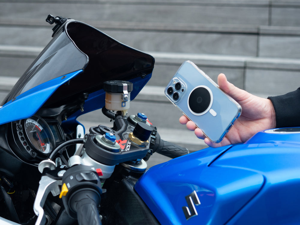 Smartphone avec plaque métal Shapeheart tenu devant le guidon d'une moto sportive